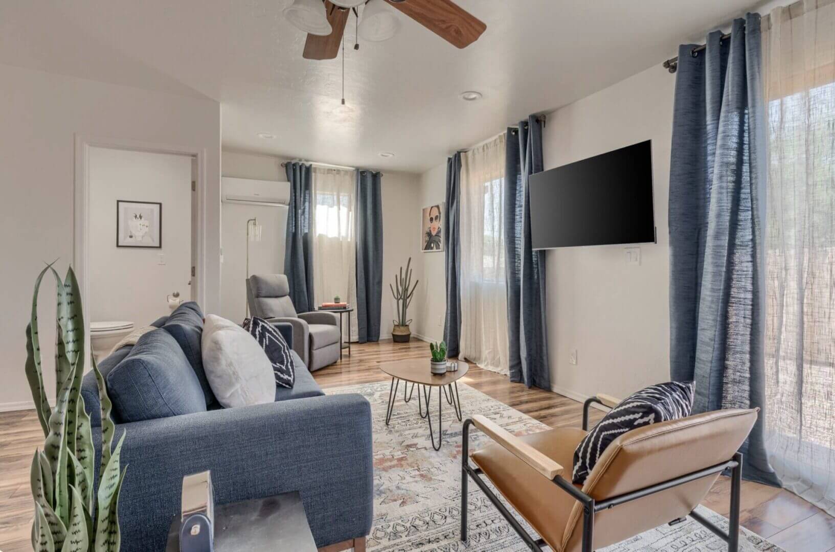 Cozy modern living room with blue sofa and wall-mounted TV.