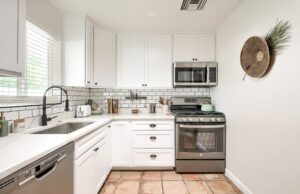 Bright white kitchen with modern appliances and tiled floor.