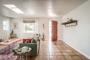 Bright living room with green sofa and open wooden door.