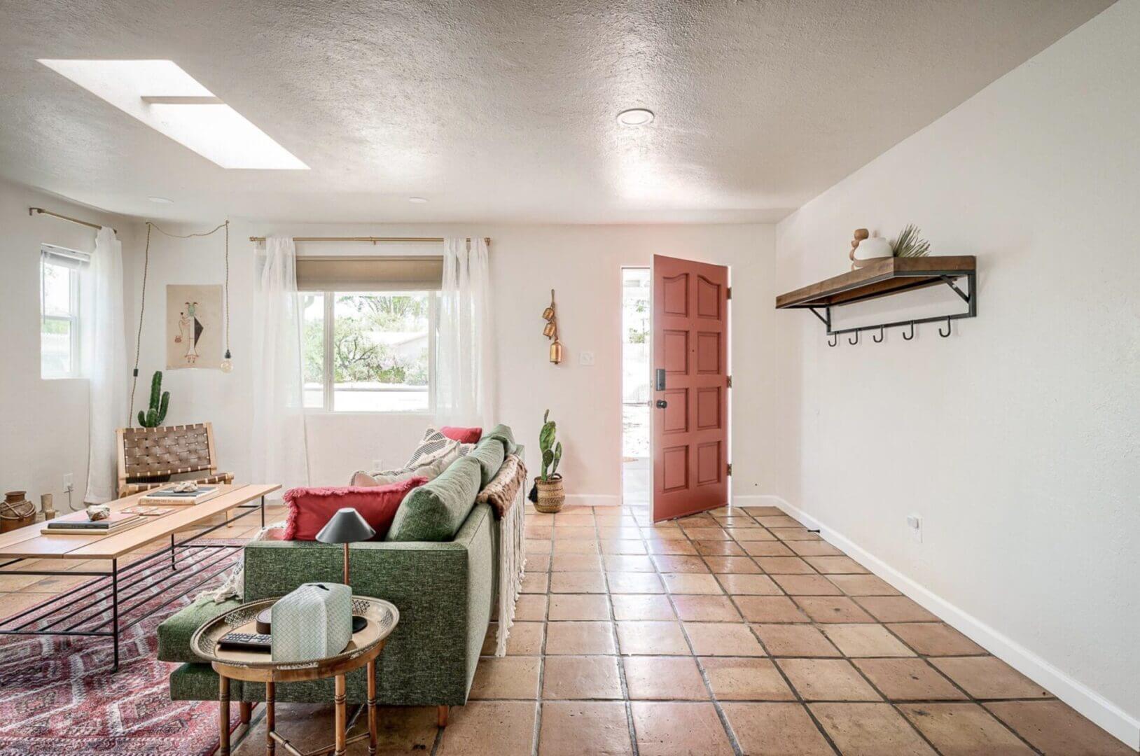 Bright living room with green sofa and open wooden door.