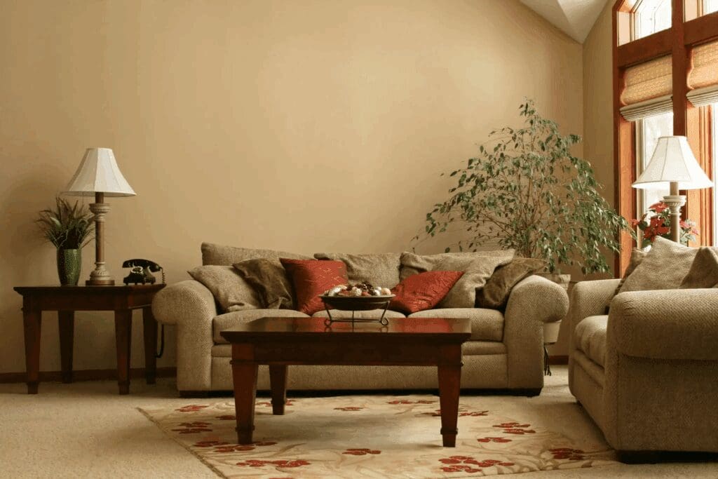 Cozy beige living room with a sofa, wooden coffee table, and potted plant.