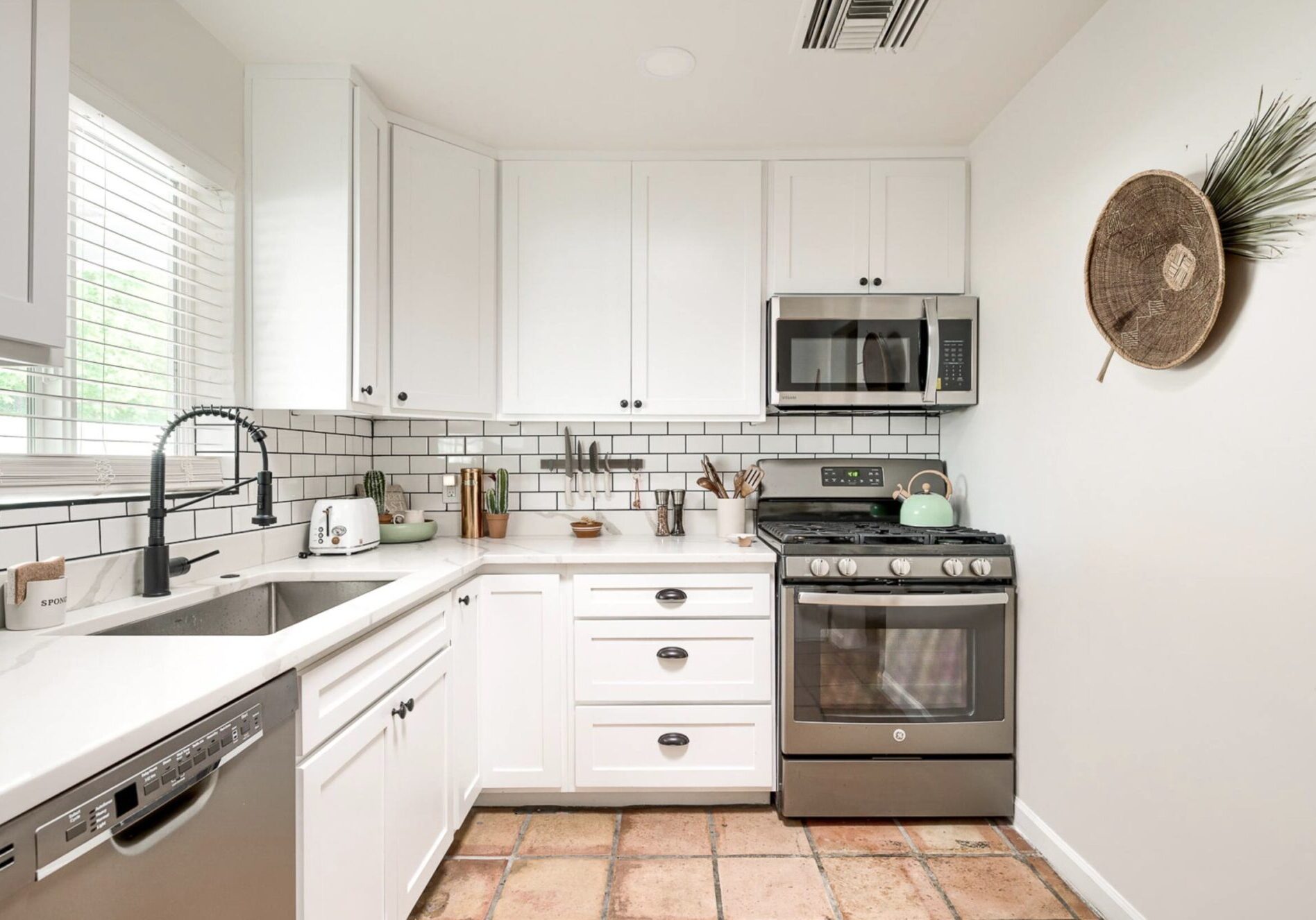 Bright white kitchen with modern appliances and tiled floor.